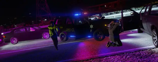 Officers detaining a person on the ground at a scene lit blue and purple