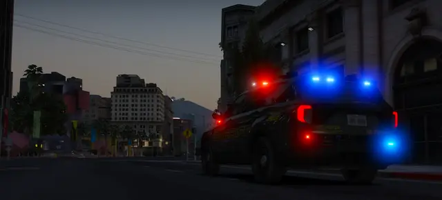 A patrol unit on a city street at first light, light bar running