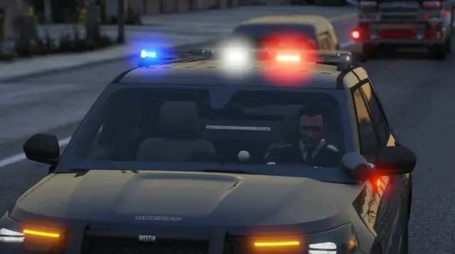 A patrol car head-on at night, the officer visible through the windscreen