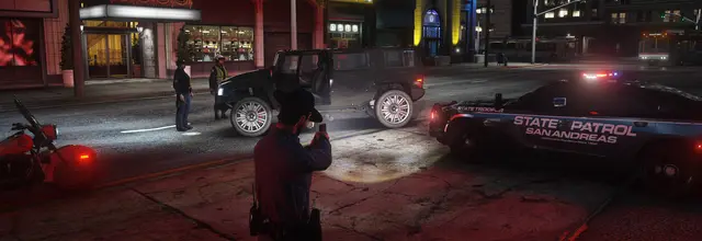 An officer standing beside a State Patrol unit in the city at night