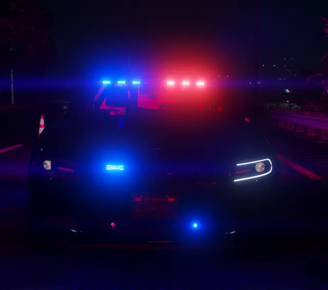A patrol car front-on at night, light bar running blue and red